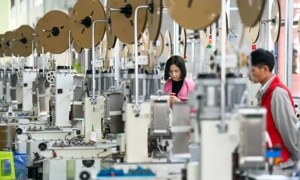 Công nhân xử lý cáp dữ liệu tại xưởng của một công ty điện tử ở khu phát triển kinh tế huyện Anlong, Trung Quốc.