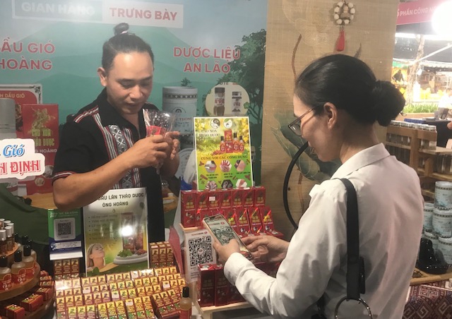 Khách hàng thanh toán bằng hình thức quét mã QR tại gian hàng sản phẩm đặc trưng địa phương. Ảnh Ngô Anh Văn