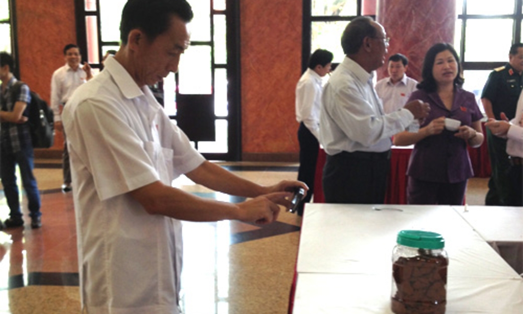 Đại biểu ghi lại hình ảnh mẫu bùn đỏ của dự án bauxite tại Tây Nguyên, được trưng bày tại hành lang Quốc hội - Ảnh: NH.<br>