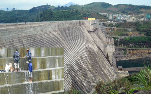 Thân đập thủy điện Sông Tranh 2 (ảnh lớn) và vết nứt khiến nước chảy xối xả - Ảnh: VTC.<br>