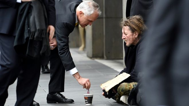 Thủ tướng Australia Malcom Turbull cho tiền người ăn xin trên đường phố Melbourne, ngày 18/8 - Ảnh: Reuters.<br>
