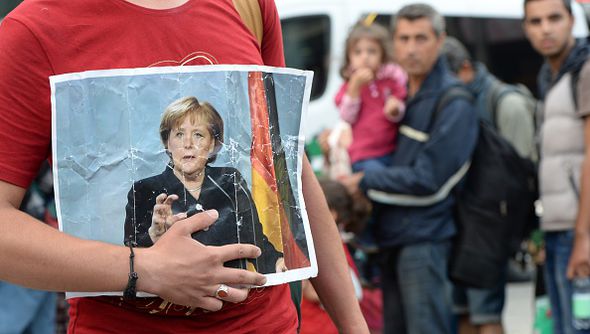 Ảnh Thủ tướng Đức Angela Merkel trên tay một người di cư tới Đức - Ảnh: Getty/Express.<br>