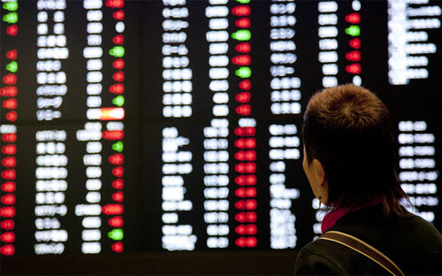 Một nhà đầu tư đang theo dõi bảng điện tử tại Sở Giao dịch chứng khoán Tokyo - Ảnh: Bloomberg.<br>