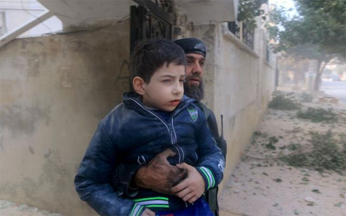 Một nhân viên cứu hộ ôm một em bé Syria bị thương sau một cuộc không kích ở Idblib, Syria ngày 20/12. Người dân địa phương và các nhân viên cứu hộ cho rằng Nga đã thực hiện cuộc không kích này - Ảnh: Reuters.<br>