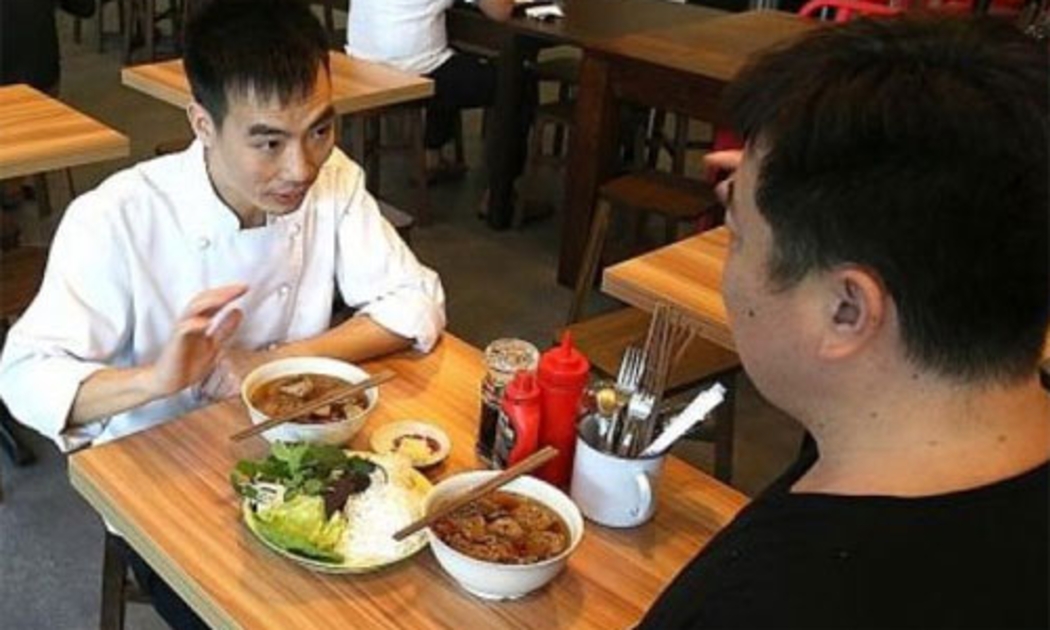 Le Van Tuan (trái), đầu bếp quán Uncle Ho, giới thiệu chi tiết về món bún chả với phóng viên - Ảnh: The New Paper.