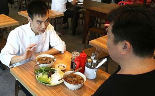 Le Van Tuan (trái), đầu bếp quán Uncle Ho, giới thiệu chi tiết về món bún chả với phóng viên - Ảnh: The New Paper.<br>