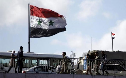 Quốc kỳ Syria bay trên một cây cầu ở Damascus ngày 14/3 - Ảnh: Reuters.<br>