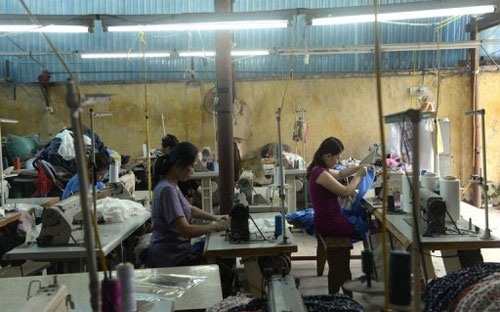 Nữ công nhân làm việc trong một xưởng may nhỏ ở ngoại ô Hà Nội hôm 2/5/2013 - Ảnh: AFP.<br>