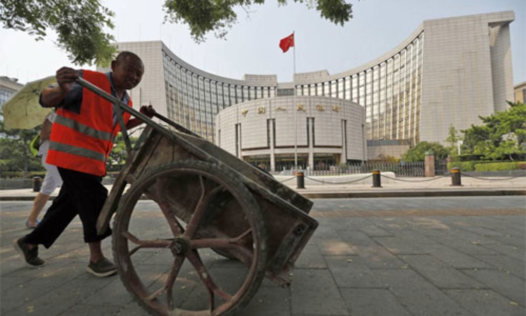 Một người công nhân đẩy xe qua trụ sở Ngân hàng Trung ương Trung Quốc (PBoC) ở Bắc Kinh - Ảnh: EPA/WSJ.<br>