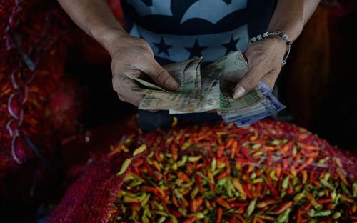 Những đồng Rupiah trong tay một người bán hàng ở Jakarta, Indonesia - Ảnh: Bloomberg/Getty.<br>