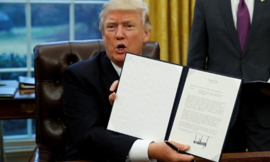 Tổng thống Mỹ Donald Trump và sắc lệnh được ông ký ngày 23/1 về rút Mỹ khỏi TPP - Ảnh: Reuters.<br>