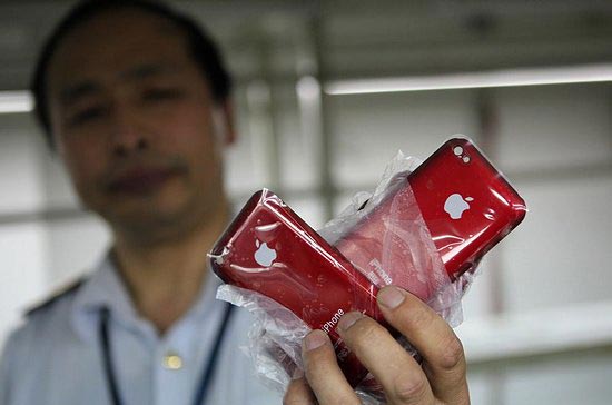 Một cảnh sát cầm trên tay bộ vỏ màu đỏ của dòng điện thoại nổi tiếng iPhone - Ảnh: MIC Gadget.