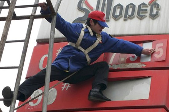 Nhân viên một trạm xăng tại Trung Quốc chỉnh sửa bảng giá. Thị trường hàng hóa thế giới diễn biến trái chiều theo số liệu lạc quan về kinh tế Mỹ - Ảnh: Reuters.