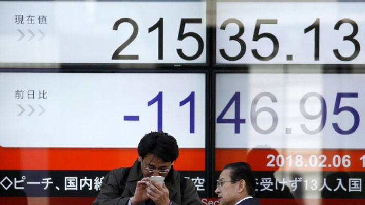 Hai người đàn ông đứng bên một bảng điện tử chứng khoán ở Tokyo, Nhật Bản, ngày 6/2 - Ảnh: Reuters.
