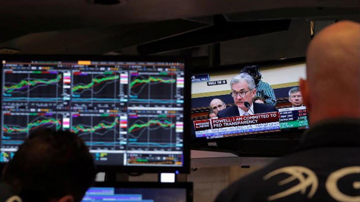 Hai nhà giao dịch cổ phiếu trên sàn NYSE ở New York đang theo dõi phiên điều trần của Chủ tịch FED Jerome Powell qua màn hình TV ngày 27/2 - Ảnh: Reuters.