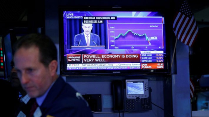 Một nhà giao dịch làm việc trên sàn NYSE ở New York, Mỹ ngày 13/6 trong lúc màn hình TV đang phát sóng tuyên bố nâng lãi suất của FED - Ảnh: Reuters.