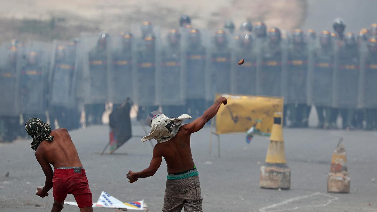 Người biểu tình ném gạch đá về phía lực lượng vệ binh quốc gia Venezuela ở biên giới giữa nước này với Brazil hôm 24/2 - Ảnh: Reuters.