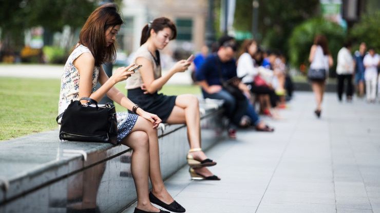Người dùng điện thoại di động trên đường phố ở quận kinh doanh trung tâm Singapore - Ảnh: Getty/CNBC.