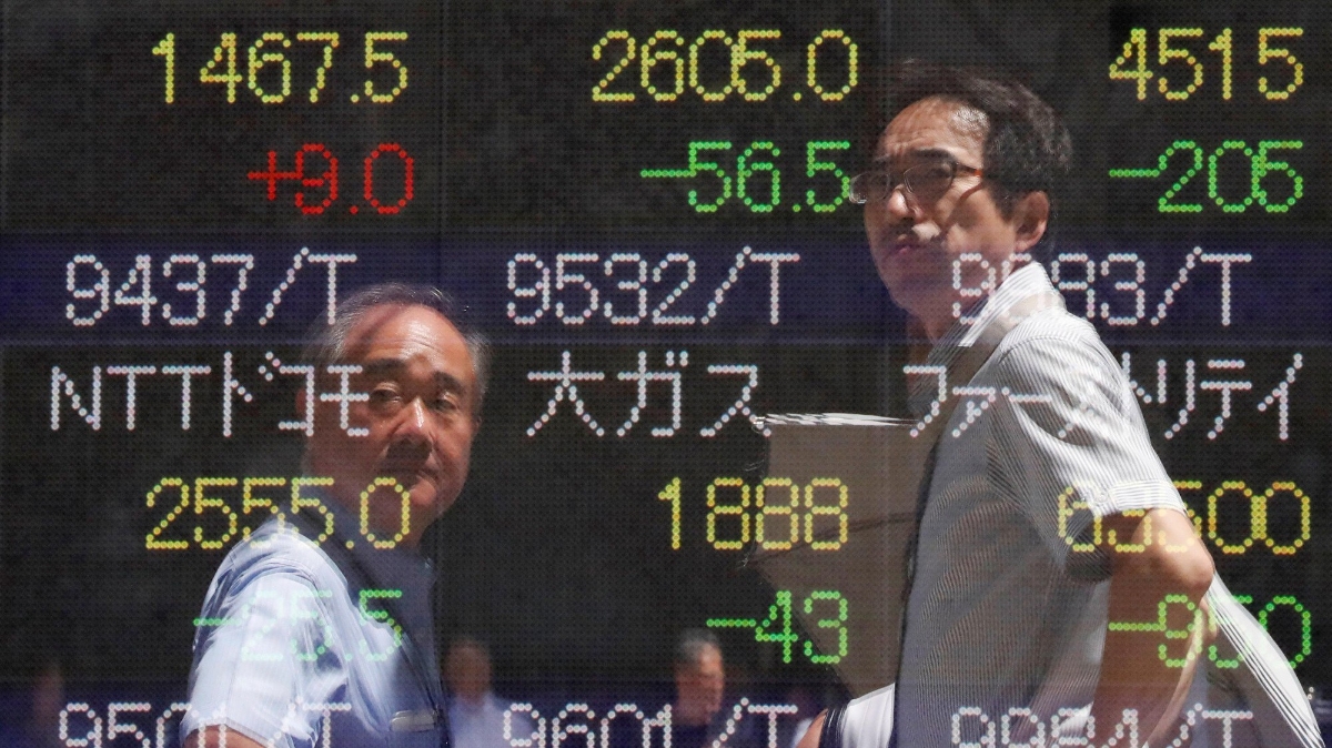 Bóng người bộ hành phản chiếu trên một bảng điện tử chứng khoán trên đường phố Tokyo ngày 6/8 - Ảnh: Reuters.