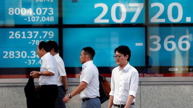 Người bộ hành đi qua một màn hình điện tử chứng khoán trên đường phố Tokyo hôm 5/8 - Ảnh: Reuters.