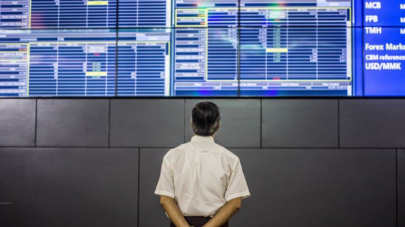 Một người đàn ông đang theo dõi giá cổ phiếu trên bảng điện tử ở Sở giao dịch Chứng khoán Yangon, Myanmar - Ảnh: Bloomberg.