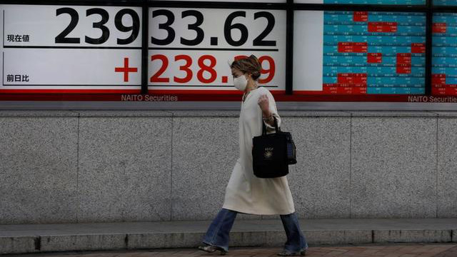 Một người bộ hành đi ngang qua một màn hình hiển thị  mức  điểm của chỉ số Nikki 225 trên đường phố ở Tokyo, Nhật Bản hôm 5/11 - Ảnh: Reuters.