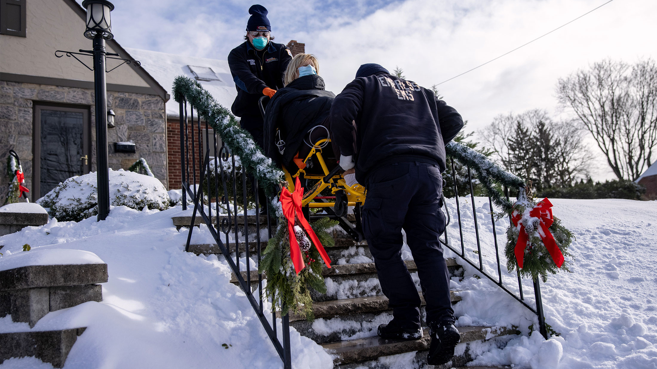 Hai nhân viên y tế đang đưa một phụ nữ có triệu chứng mắc Covid-19 tới bệnh viện ở Yonkers, New York, hôm 17/12 - Ảnh: Bloomberg.