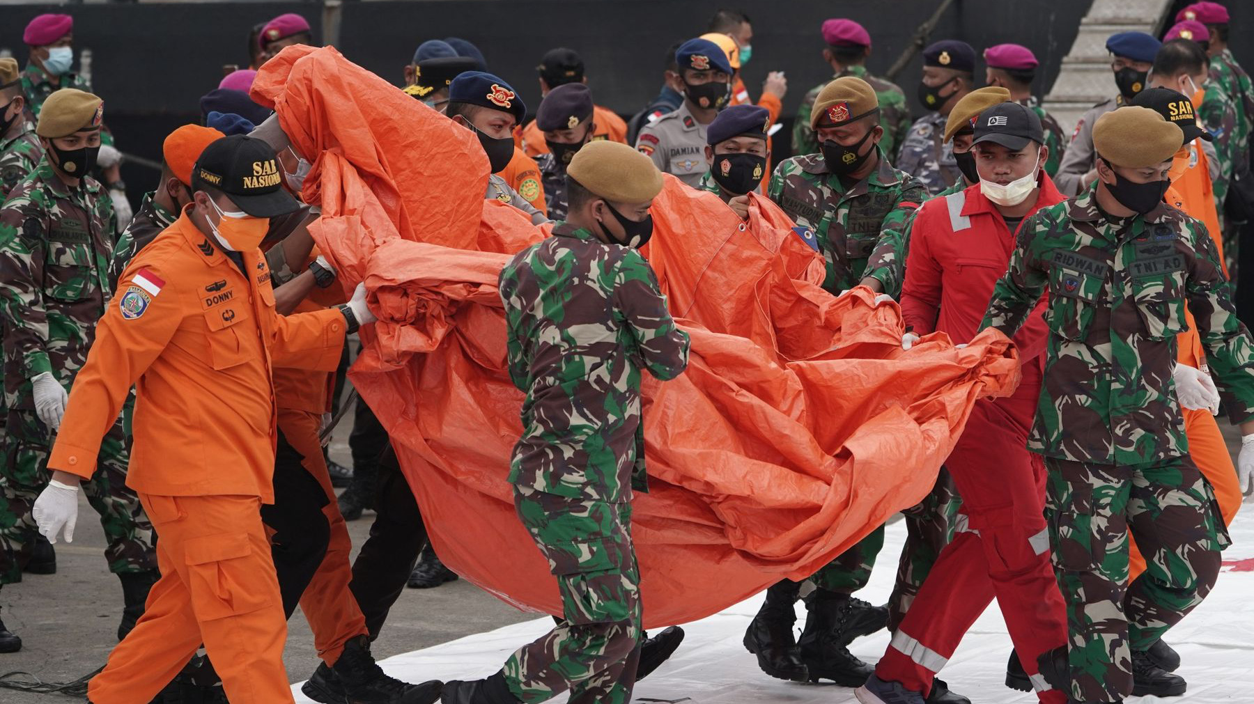 Nhân viên tìm kiếm cứu hộ mang các mảnh vỡ trục vớt từ hiện trường vụ tai nạn máy bay của hãng Sriwijaya Air - Ảnh: Bloomberg