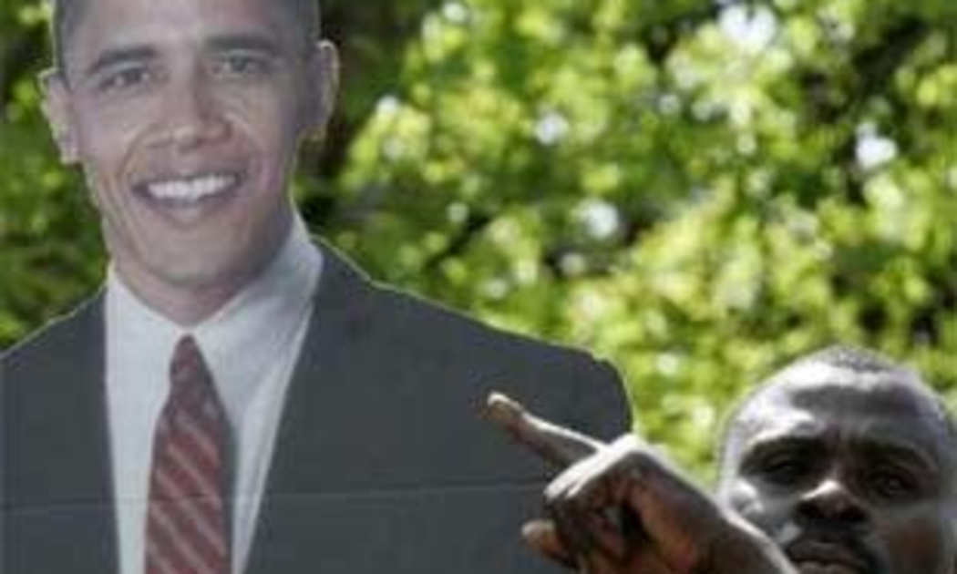 Một người đàn ông ở làng Kogelo (Kenya) - quê cha của Obama - giơ cao tấm biểu ngữ in hình vị Tổng thống mới đắc cử của nước Mỹ - Ảnh: Reuters.