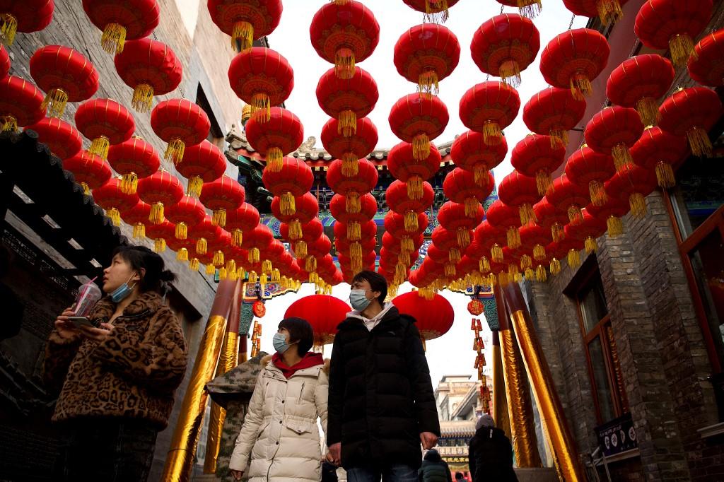 Người dân đi bộ dưới những chiếc đèn lồng truyền thống của Trung Quốc dọc theo một con hẻm ở Bắc Kinh dịp năm mới - Ảnh: AFP