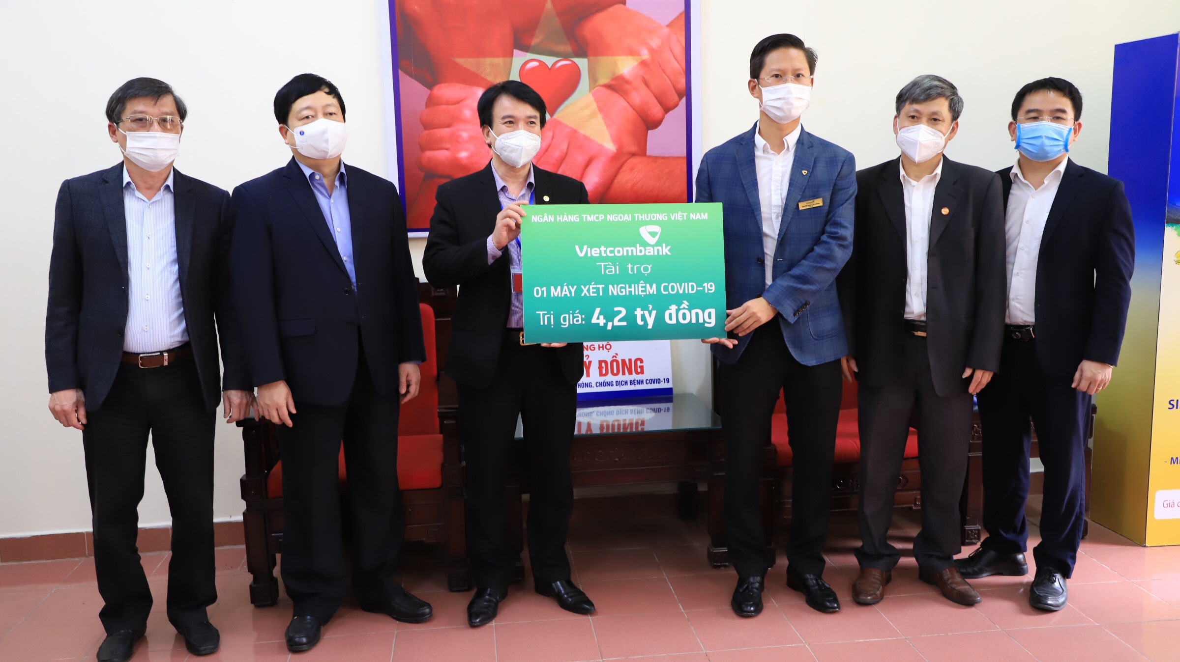 Ông Nguyễn Xuân Cao Cường - Giám đốc Vietcombank Hải Dương (thứ ba từ phải sang), thay mặt Ban lãnh đạo Vietcombank trao biển tài trợ 1 máy xét nghiệm COVID-19 cho tỉnh Hải Dương.