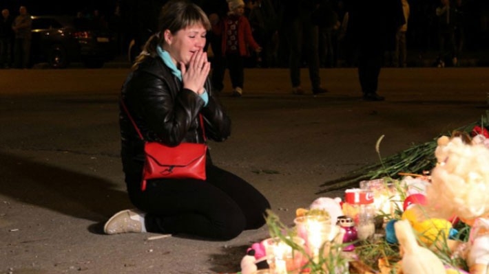 Một người phụ nữ trong lễ tưởng niệm các nạn nhân vụ xả súng trường học ở Crimea ngày 17/10 - Ảnh: Reuters.