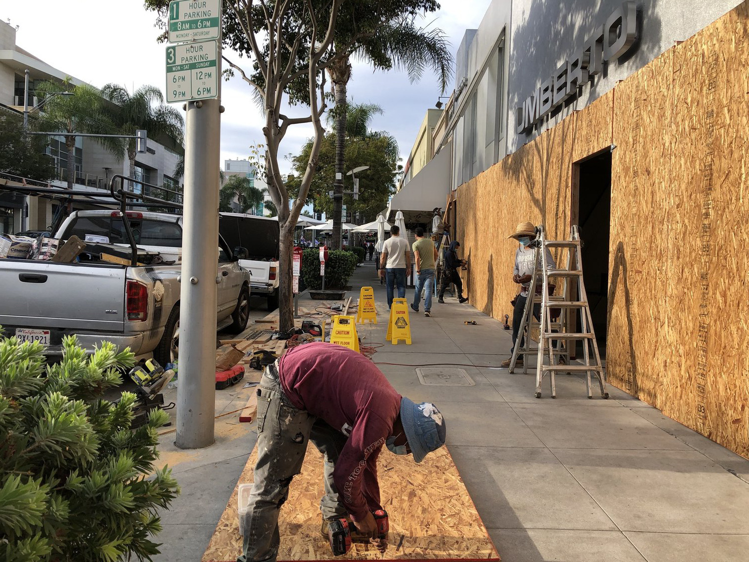 Các công nhân làm gia cố một cửa hàng tại Beverly Hills, California cuối tuần trước - Ảnh: NPR.
