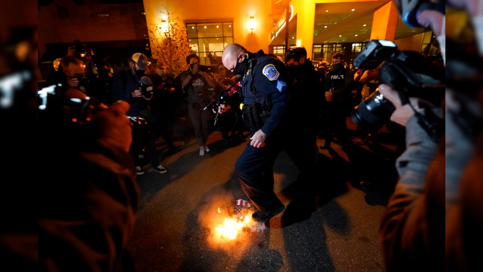 Cảnh sát đã phải can thiệt để ngăn bạo lực trở nên nghiêm trọng. Trong ảnh là một sĩ quan cảnh sát dập lửa sau khi một người phản đối ông Trump đốt cờ - Ảnh: AP