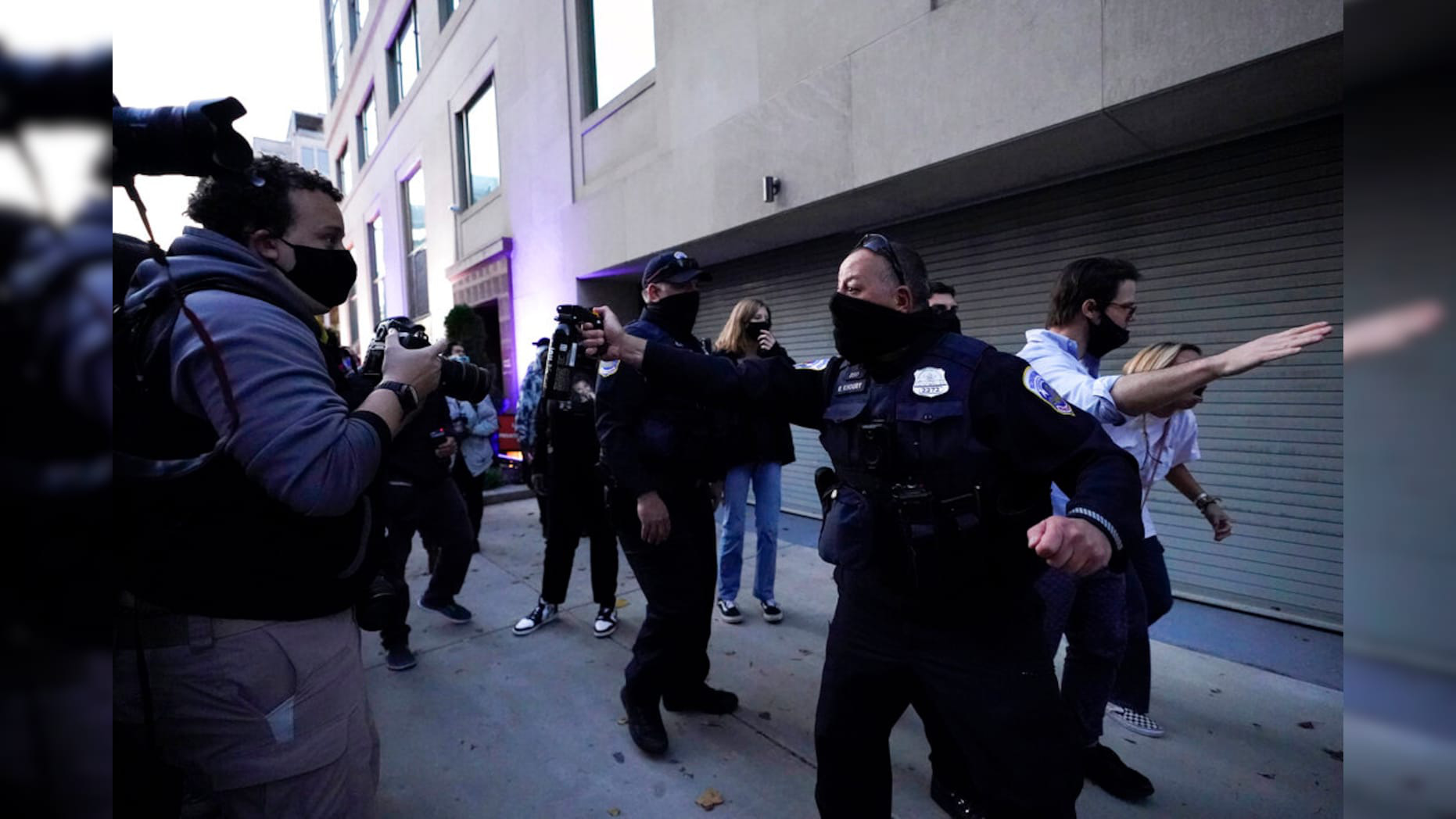 Một sĩ quan cảnh sát dọa xịt hơi cay vào đám đông sau khi giúp một người phụ nữ rời khỏi khu vực biểu tình ủng hộ ông Trump - Ảnh: AP