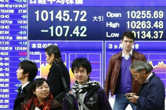 Phía trước một bảng điện tử chứng khoán trên đường phố Tokyo (Nhật Bản). Tính theo tỷ lệ nợ công so với GDP, thì Nhật Bản còn nặng nợ hơn cả Mỹ - Ảnh: AP.