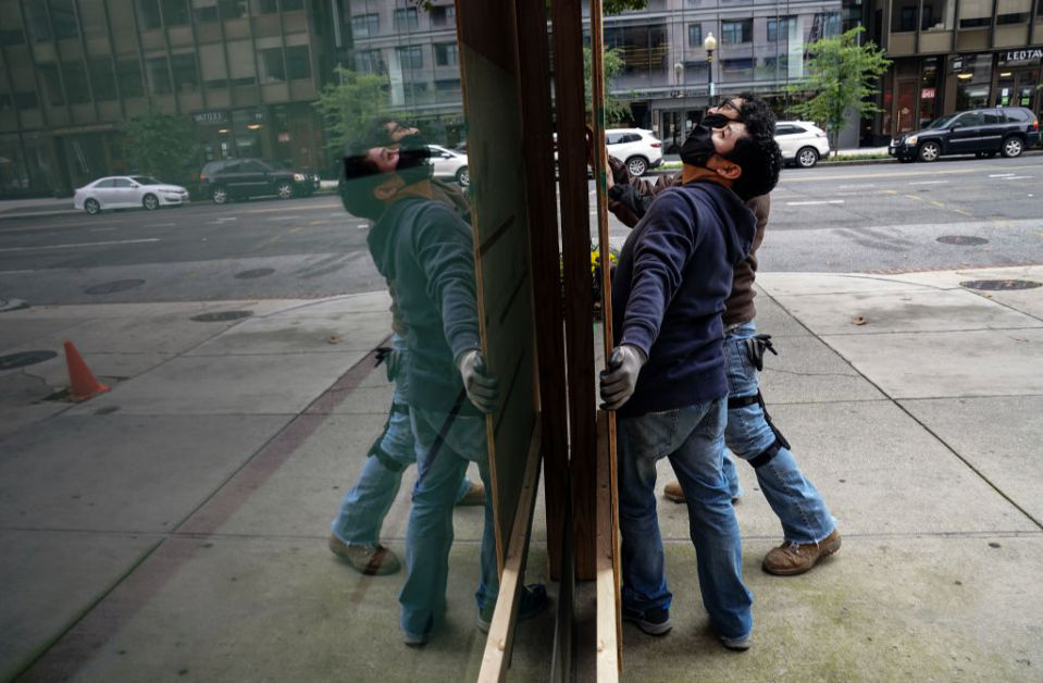 Công nhân dùng ván ép để che cửa sổ kính trước tòa nhà ở Phố 17, Washington, DC - Ảnh: Getty Images.