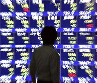 Khách bộ hành theo dõi bảng giá chứng khoán trên đường phố Tokyo (Nhật). Trong thập niên 1990, Nhật Bản đã trải qua những thách thức tương tự như những gì đang diễn ra ở Mỹ và châu Âu hiện nay - Ảnh: Reuters.
