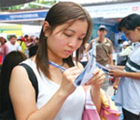 Người đi tìm việc đang ghi chép thông tin về nhà tuyển dụng tại một hội chợ việc làm vừa được tổ chức ở Tp.HCM.