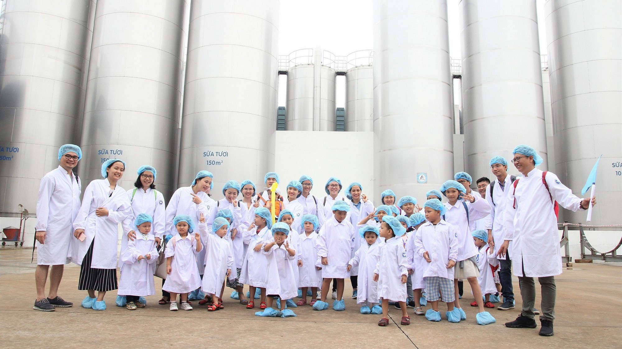 Các bé chụp ảnh cùng bố mẹ tại khu vực bồn chứa sữa tươi khổng lồ của nhà máy.