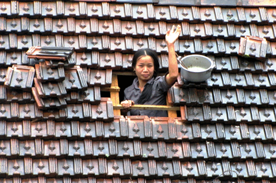 Một người phụ nữ dỡ mái ngói vẫy tay cầu cứu. Ảnh: Nguyên Khoa.