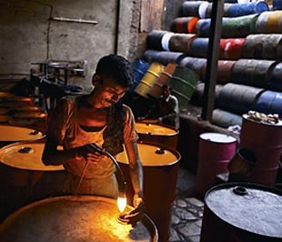 Một công nhân Ấn Độ đang kiểm tra các thùng đựng dầu trong kho chứa. Ở Mỹ, dầu thường được đựng trong các bể chứa khổng lồ.