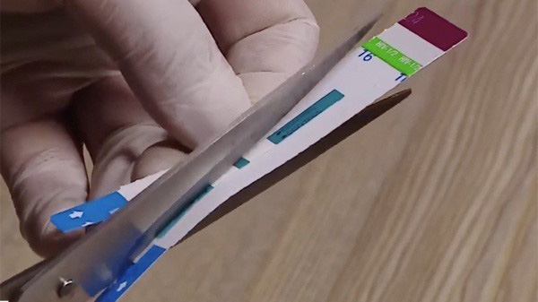 Hình ảnh nhân viên y tế cắt đôi que thử xét nghiệm từ clip phản ánh của báo chí tại Bệnh viện Xanh Pôn. 