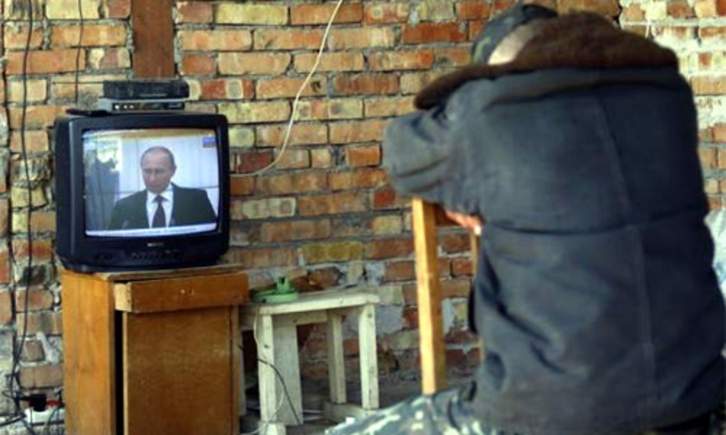 Một người dân Ukraine lắng nghe bài phát biểu của Tổng thống Nga Putin về việc tiếp nhận Crimea trên truyền hình - Ảnh: Reuters.<br>