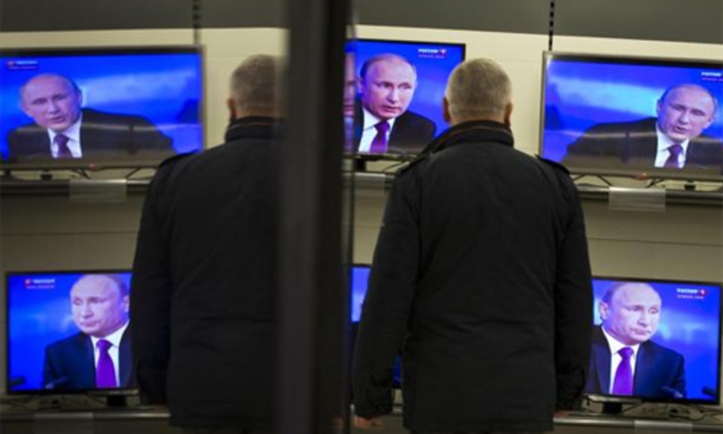 Một người đàn ông xem Tổng thống Nga Vladimir Putin phát biểu trên TV, tại một siêu thị điện máy ở Moscow hôm 18/12 - Ảnh: AP.<br>