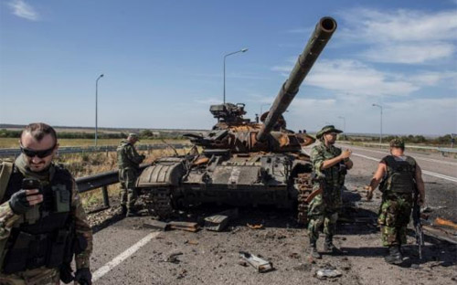 Binh sỹ nổi dậy bên một chiếc xe tăng gần như đã bị phá hủy ở Luhansk, miền Đông Ukraine - Ảnh: Reuters.<br>