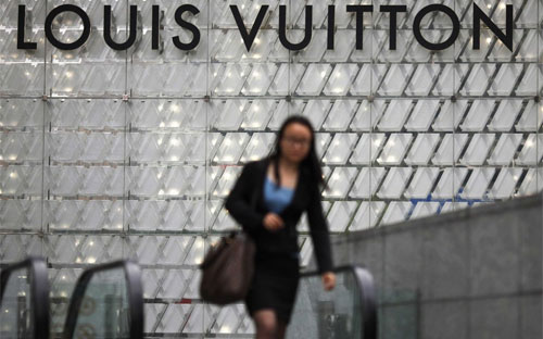 Một phụ nữ đi qua một cửa hiệu Louis Vuitton ở Thượng Hải, Trung Quốc - Ảnh: Reuters/BI.<br>
