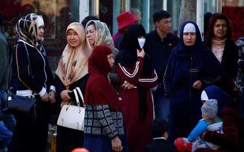 Phụ nữ người Duy Ngô Nhĩ đứng chờ xe bus ở Urumqi, thủ phủ Tân Cương, Trung Quốc - Ảnh: Reuters.