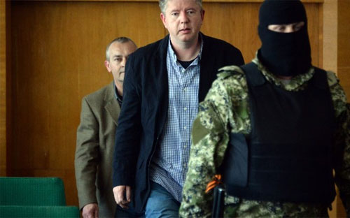 Một phần tử ly khai thân Nga dẫn các con tin là quan sát viên của Tổ chức An ninh và Hợp tác châu Âu (OSCE) tới một cuộc họp báo ở Slaviansk vào ngày Chủ nhật ngày 27/4 - Ảnh: AFP/Getty.<br>