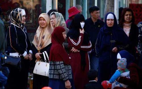 Phụ nữ người Duy Ngô Nhĩ đứng chờ xe bus ở Urumqi, thủ phủ Tân Cương, Trung Quốc - Ảnh: Reuters.<br>